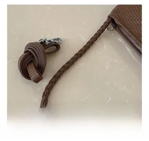 Detail of woven leather texture on a dark brown hobo bag with a circular handle