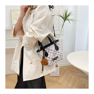 Detail of plaid bucket bag with gold logo plaque and cute plush dog charm accessory