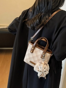 Mini plaid tote bag with brown handles and a white plush bunny charm on a black coat