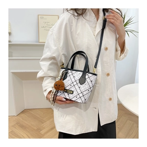 Close-up of mini bucket bag with black checkered pattern and cute bear plush charm
