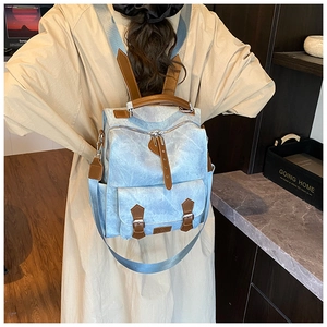 Detail of light blue vintage backpack showing distressed texture and brown leather straps