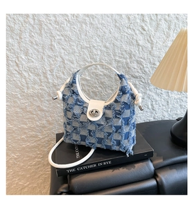 Detail of plaid denim bucket bag with frayed edges, silver twist lock and leather strap
