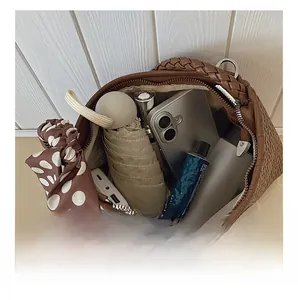 Detail view of the spacious interior of a brown woven shoulder bag with daily essentials