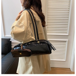 Detail of black glossy pleated Boston bag with long straps and mini pouch