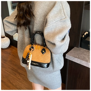 Detail of vintage shell bag with brown suede, black leather and tassel on gray sweater