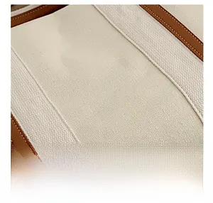 Vue détaillée du tissu en toile de qualité avec coutures en cuir marron sur le sac cabas
