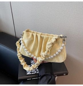 Détail du sac plissé jaune pâle avec une élégante chaîne de perles fantaisie surdimensionnée