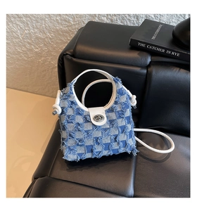 Detail of checkered denim bucket bag with frayed edges and silver metal twist lock