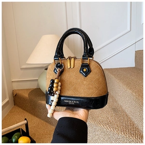 Detail of contrast stitching shell bag with quilted brown suede and wooden bead charm