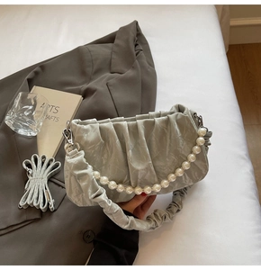 Détail du sac nuage vert sauge avec poignée en perles et texture en cuir plissé élégant