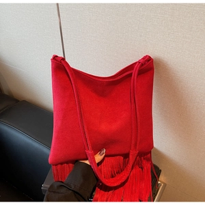 Dettaglio borsa a spalla in camoscio rosso con lunghe frange e design a tracolla sottile
