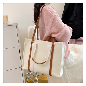 Détail du grand sac cabas en toile blanc cassé avec anses marron porté par un mannequin