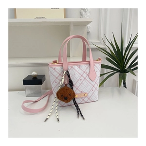 Detail of pink plaid bucket bag showing plush bear charm and metallic brand nameplate