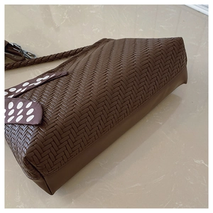 Close-up of deep brown woven hobo bag featuring a polka dot scarf on the shoulder strap