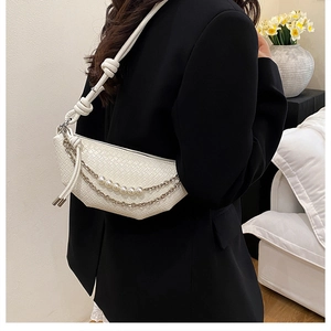 Détail du sac croissant tressé blanc avec chaîne argentée et perles porté par un mannequin