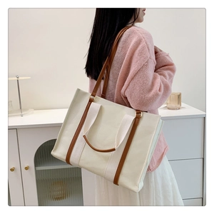 Détail du sac cabas en toile avec anses en cuir marron montrant coutures et texture