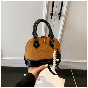 Detail view of a vintage shell bag with brown quilted suede and black leather accents