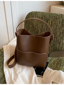 Brown leather bucket bag with white contrast stitching on a vintage chair