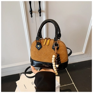 Detail of quilted two-tone shell bag featuring brown suede and black faux leather