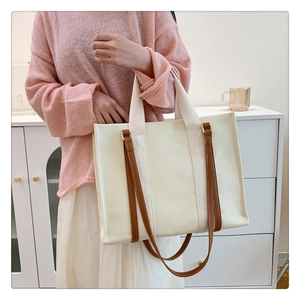Détail du cabas en toile blanche avec sangles en cuir marron et poignées tissées