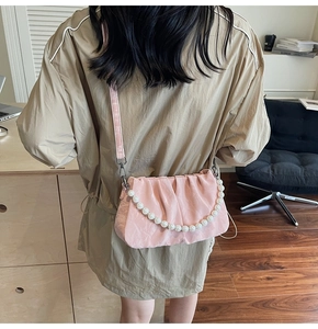 Détail du sac nuage plissé rose avec une grande bandoulière en perles sur modèle