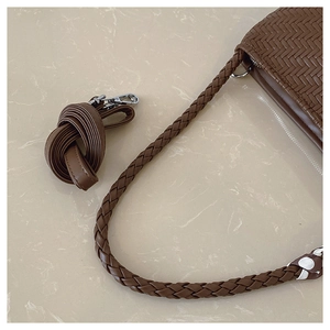 Detail of brown woven leather texture with dual straps and silver metal hooks