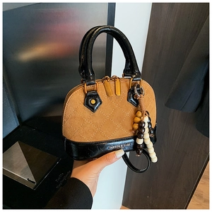 Close-up of brown shell bag with quilted texture, bead tassel and fashion logo
