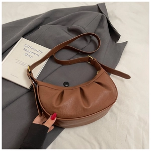 Détail du sac demi-lune plissé marron avec texture litchi et boucle réglable dorée