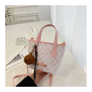 Detail of pink plaid bucket bag with plush bear charm and woven rope handle