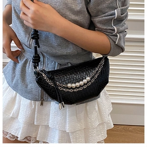 Detail of a black woven crescent bag with decorative pearl and metal chain straps
