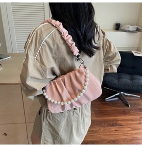 Détail du sac nuage plissé rose clair avec grande chaîne en perles et bandoulière assortie