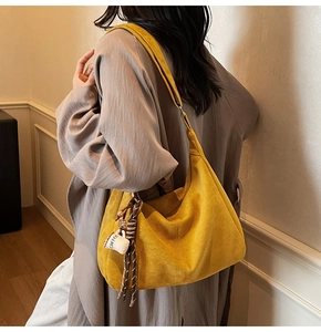Detail view of mustard yellow suede tote with decorative coffee cup charm and rope knot