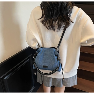 Blue denim crossbody bag featuring a unique black spiral handle and detachable strap