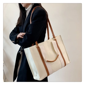 Détail du sac fourre-tout en toile avec bordure en cuir marron porté par un mannequin