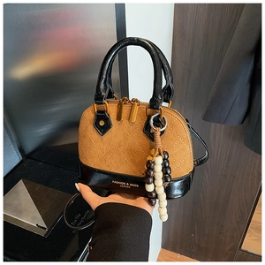 Detail of color-block shell bag featuring quilted suede texture and beaded charm