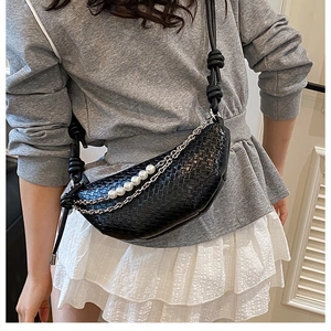 Gros plan du sac croissant noir tissé avec des perles et une chaîne argentée