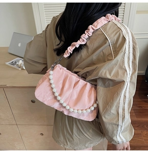 Détail du sac nuage plissé rose avec chaîne de perles élégante et texture froncée