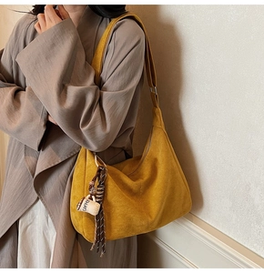 Detail of mustard yellow suede tote bag with a coffee cup charm and woven tassel