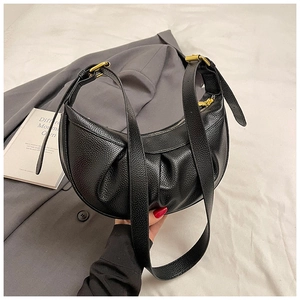 Détail du sac demi-lune noir avec texture grainée, plis et fermeture éclair dorée