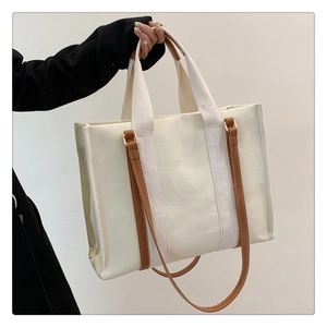 Gros plan d'un sac cabas en toile avec anses en cuir marron et bandoulière réglable