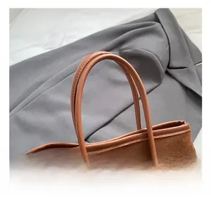 Detailed close-up of brown suede tote bag with leather handles and silver metal hardware