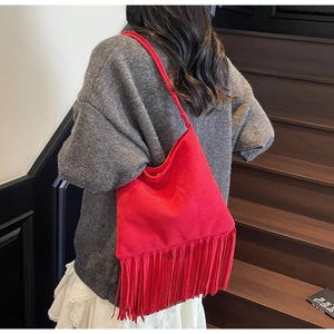Dettaglio di borsa a tracolla in pelle scamosciata rossa con frange indossata da modella