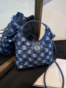 Denim checkerboard bucket bag with frayed edges and silver twist lock on a mirrored surface