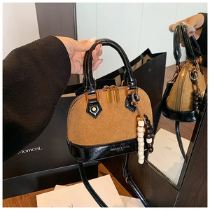 Detail of vintage shell-shaped crossbody bag with brown quilted texture and black trim