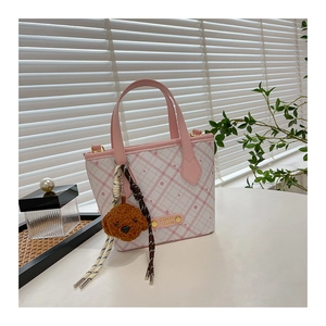 Detail view of pink plaid bucket bag with gold logo and plush bear charm accessory
