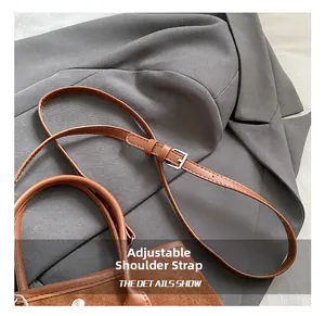 Detail of adjustable leather shoulder strap with a metal buckle on a brown tote bag