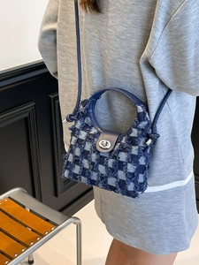 Blue denim checkered bucket bag with fringes and silver metal clasp on a model