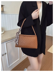 Detailed view of brown woven texture handbag with polka dot silk scarf handle