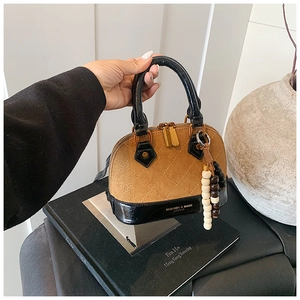 Detail of shell handbag with diamond stitching, brown suede texture, and wood bead charm