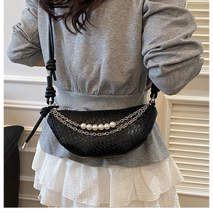 Détail d'un sac demi-lune noir tressé avec chaînes argentées et perles blanches